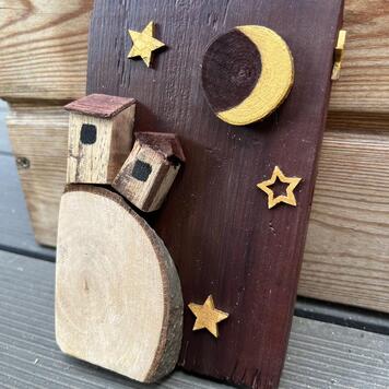 Décoration en bois peinte à la main — deux maisonnettes sur une rondelle de bois sous un croissant de lune doré et des étoiles sur fond bordeaux