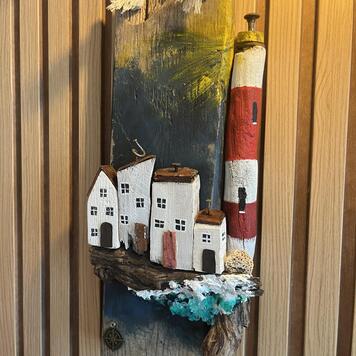 Décoration murale en bois peinte à la main — maisonnettes blanches et phare rouge et blanc sur une vieille planche avec boussole et vague écumante