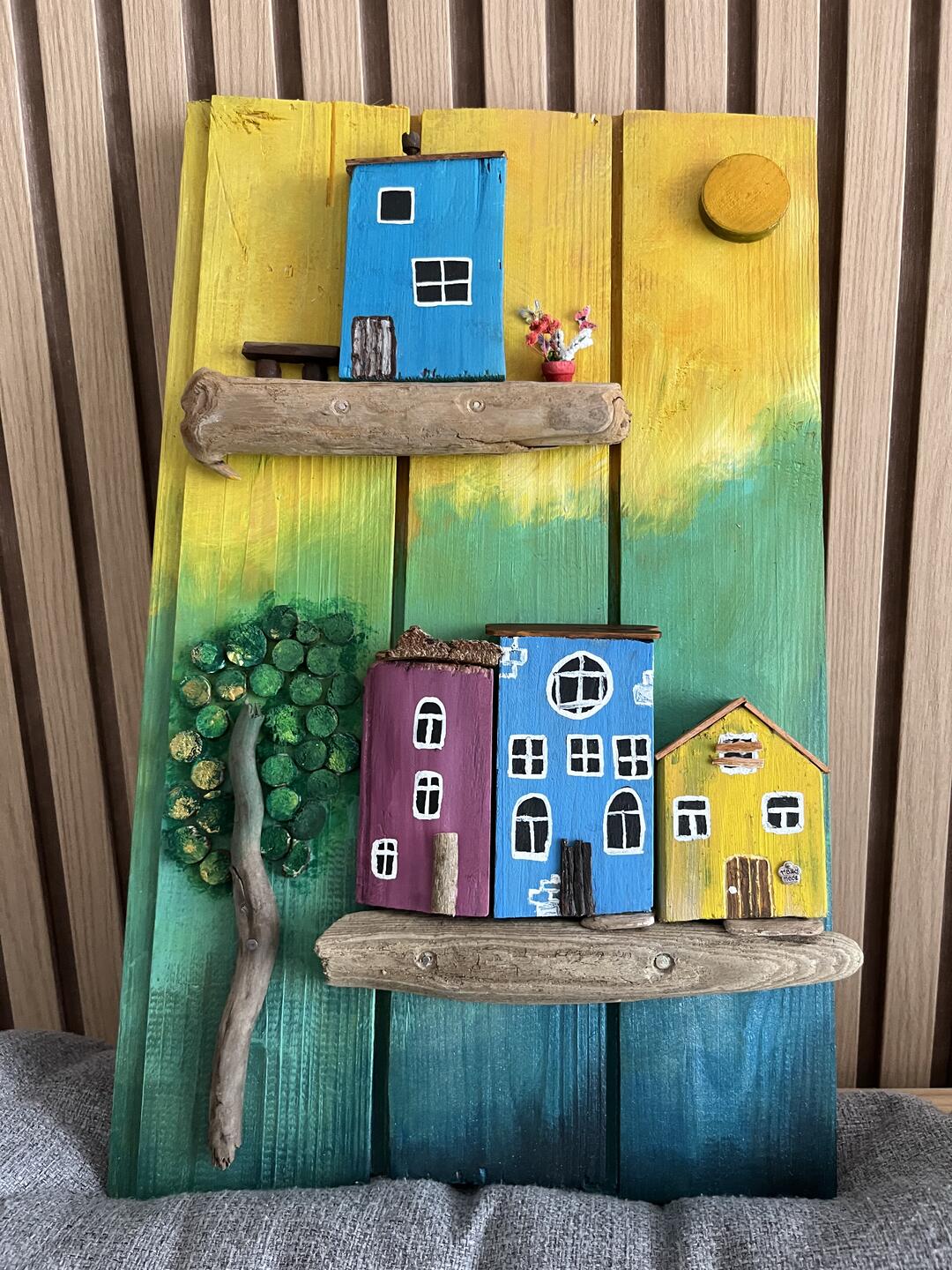 Decorazione in legno dipinta a mano — casette colorate su mensole di legno di mare, un albero e un sole su sfondo giallo, verde e blu — foto 1 / 4