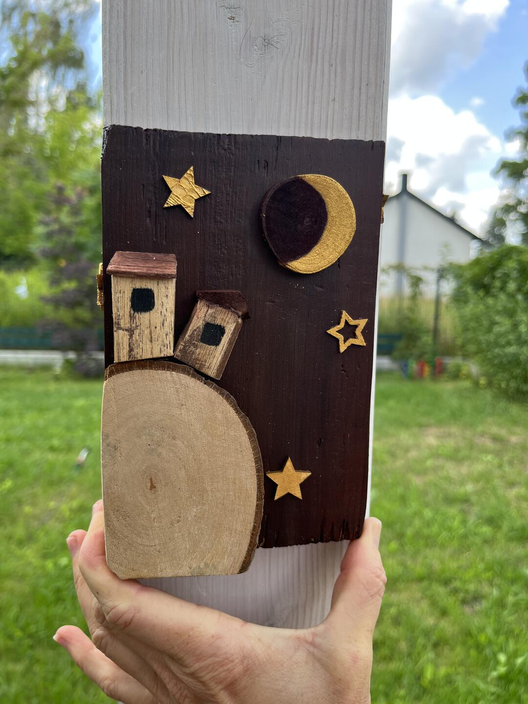 Decorazione in legno dipinta a mano — due casette su una fetta di legno sotto una falce di luna dorata e stelle su sfondo bordeaux — foto 3 / 4